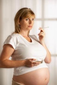 ATTRACTIVE HEALTHY YOUNG PREGNANT WOMAN SMOKING CIGARETTE.